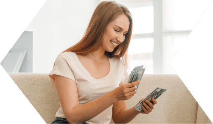 Woman smiling, counting money on couch.